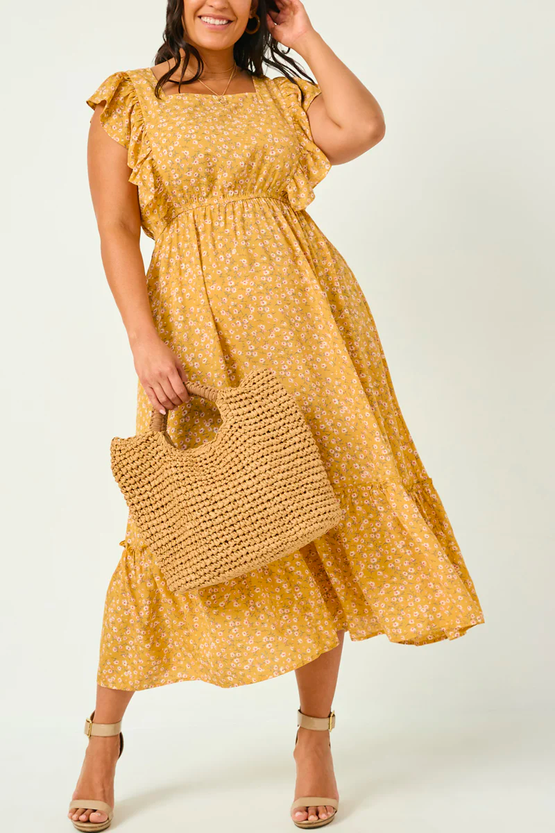 A curvy woman poses in a square bodice dress and a matching bag. 