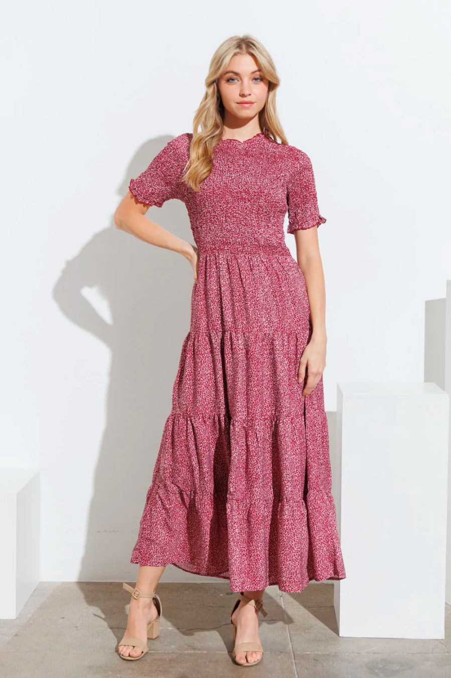 A woman with curtain bangs wears a soft floral maxi. 