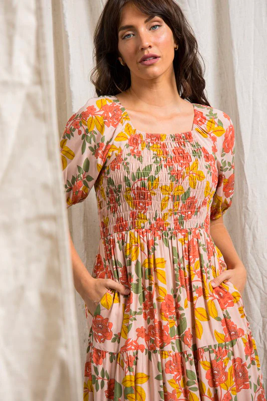 A model poses in a floral maxi dress with pockets.