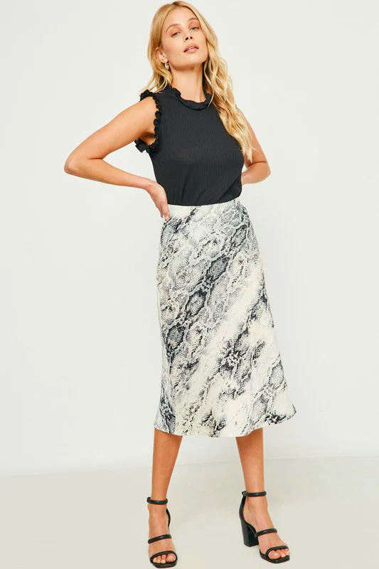 A woman wears a printed skirt with a ruffled black top. 
